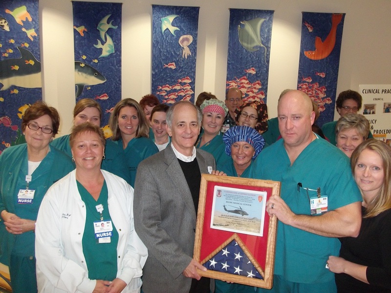 Pictured at the presentation of the U.S. flag and plaque to hang in the lobby of Same Day Surgery at Beebe are in back (l-r) Debbie Brittingham, Kelley Stein, Gerri Davis and Gretchen Kinsler; third row, Wendy Scott, Kat Riley, Ashley Touchton, Jeannine Holland, Tina Gland, Paul Hollenbach and Annette Wright; second row, Mimi Hernandez, Jenna Blades, Sherri Black-Hauth and Tracy Williams; front, Vicki Evans, Jeffrey Fried, Chris Willey and Carol Willey. SOURCE SUBMITTED